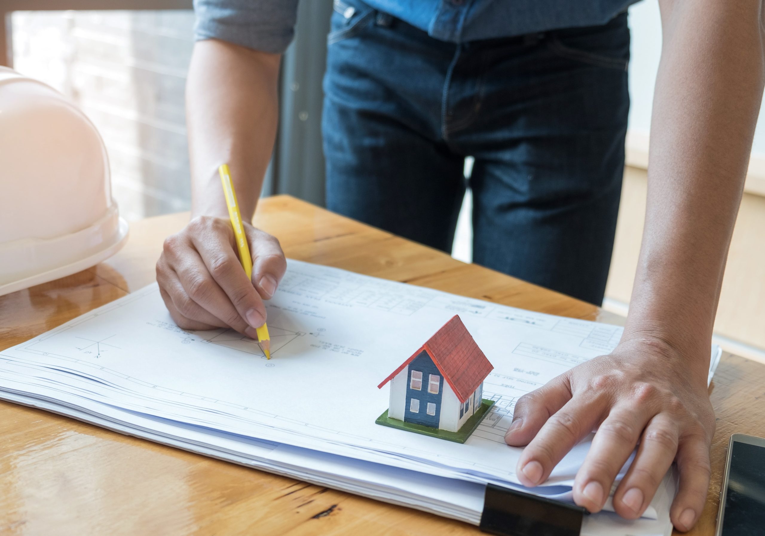 architect holding a yellow pencil drawing house pl ZY2L9TN min scaled