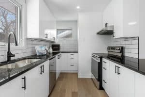 a kitchen with white cabinets and black counter tops